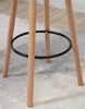 Close-up of the base of a bar stool, showing the wooden legs and a black metal footrest ring. Podgląd zdjęcia produktu