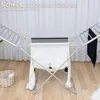 An electric heated clothes drying rack with white and black laundry hanging on it, set against a white curtain background and a wooden floor. Produktbild-Vorschau