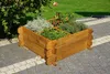 A wooden planter box filled with herbs and small tomato plants sits on a paved patio next to a garden. Náhled obrázku produktu