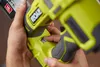 A person's hands are holding a yellow and gray power tool, with a finger pressing a switch. Anteprima dell’immagine prodotto