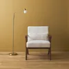 A cream bouclé armchair with a wooden frame and a gold floor lamp against a mustard yellow wall. Anteprima dell’immagine prodotto