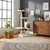 A cat tree with cats on it, placed in a living room setting with plants and a dresser. Podgląd zdjęcia produktu