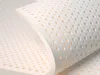 A close-up, angled view of a white latex mattress topper with many small, circular perforations. Produktbild-Vorschau
