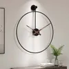 A large, minimalist metal wall clock with a black frame and brown hands is mounted on a white wall above a wooden console table. Anteprima dell’immagine prodotto
