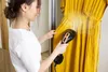 A woman is steaming a yellow dress in front of a wardrobe. Podgląd zdjęcia produktu