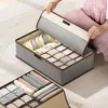 A person's hands are opening a fabric storage box with multiple compartments for organizing clothes. Produktbild-Vorschau