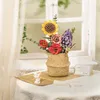 A miniature bouquet of artificial flowers in a woven basket, placed on a table near a window. Produktbild-Vorschau