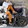 A person is sitting in the open trunk of a car with a folded electric bicycle next to them. Produktbild-Vorschau