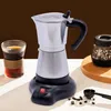 A silver electric espresso maker with a black base and handle, placed on a white surface with a glass of coffee and coffee beans nearby. Náhled obrázku produktu