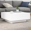 A white coffee table with a plant and cup on it, placed in front of a gray sofa. Náhľad obrázku produktu