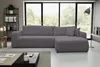 A dark gray sectional sofa is shown in a modern living room with large windows overlooking trees. A coffee table with a candle and books is in the foreground. Voir les images du produit