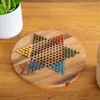 A wooden Chinese Checkers board with colorful marbles is placed on a wooden table, next to a white potted plant. Produktbild-Vorschau