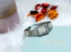A watch is placed on a light blue notebook with gold lettering, surrounded by decorative potpourri and a candle. Podgląd zdjęcia produktu