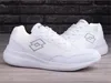 A pair of white Lotto sneakers are displayed on a wooden surface with a brick wall in the background. Produktbild-Vorschau