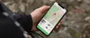 A person holding a smartphone with a navigation app open, likely outdoors. Produktbild-Vorschau