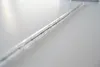 A close-up, angled shot of a clear glass tube with a black wire running through it, resting on a white surface. Produktbild-Vorschau