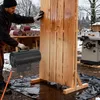 A person is working on a wooden structure outdoors in winter, using a heater. Produktbild-Vorschau