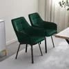 Two green velvet dining chairs are shown in a room with a light-colored rug and a table. Voir les images du produit