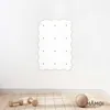 A white climbing wall module with multiple attachment points is mounted on a white wall above a wooden floor. Two wooden dumbbells and a textured ball are on the floor in front of the wall. Produktbild-Vorschau