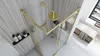 A modern bathroom with a gold-framed shower enclosure, a shower head, and toiletries on a shelf. Produktbild-Vorschau