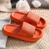 Paar leuchtend orangefarbene Pillow-Slides mit dicken Sohlen und strukturierten Riemen, auf gewebter Matte Náhľad obrázku produktu
