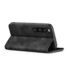 A black flip case for a smartphone is shown open, with the phone inserted and its camera array visible. Produktbild-Vorschau