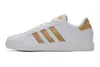 A side view of a white Adidas sneaker with gold stripes. Produktbild-Vorschau