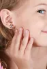 Close-up of a young girl's ear with a small earring, her hand touching her cheek. Produktbild-Vorschau