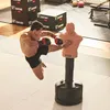 A man is practicing martial arts by kicking a dummy in a gym. Podgląd zdjęcia produktu