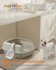 A cat stands next to an open litter box with a scoop, in a clean bathroom setting. Produktbild-Vorschau