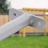 A close-up of a gray metal bar with mounting holes, set against a blurred outdoor background of grass and a wooden structure. Produktbild-Vorschau