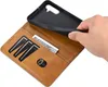 A hand is holding a black phone case over a brown wallet-style phone case with card slots and a bill compartment. Produktbild-Vorschau
