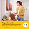 A woman is placing a breast pump accessory into a bag, with other accessories and a plant on a table. Voir les images du produit