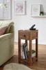 A wooden side table with books and a phone sits next to a sofa in a living room. Náhled obrázku produktu