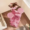 A cat is sleeping on a pink cat tree in a room with wooden floors and a sofa. Produktbild-Vorschau
