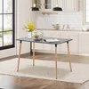 A rectangular dining table with black top and wooden legs is set up in a kitchen or dining area, with a vase of flowers, fruit, and bottles on it. Voir les images du produit