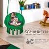 A young girl and a puppy are sitting in a green hanging chair in a room. Podgląd zdjęcia produktu