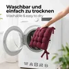 A hand is holding a burgundy seat cushion in front of an open washing machine. Voir les images du produit