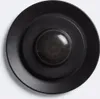 A close-up, top-down view of a black motion sensor with a domed lens. Produktbild-Vorschau