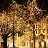 A street decorated with trees wrapped in warm white LED lights at night. Produktbild-Vorschau