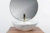 A close-up shot of a marble sink with a gold faucet in front of a round mirror. Anteprima dell’immagine prodotto