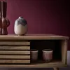 A close-up of a wooden coffee table with decorative vases and cups on top and inside. Produktbild-Vorschau