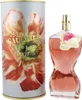 Parfumflakon in Form eines Frauenkörpers mit Blume am Hals, daneben zylindrische Dose mit Blütenmotiv und goldener Schrift „La Belle Flower Edition“. Anteprima dell’immagine prodotto