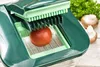 A close-up of a tomato being sliced by a kitchen gadget. Produktbild-Vorschau