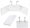 Multiple views of a white, foldable cosmetic mirror with clear side panels and metal hooks for hanging. Produktbild-Vorschau