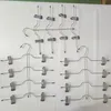 Multiple metal hangers with clips, arranged in rows on a white surface. Produktbild-Vorschau