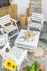 A patio set with white chairs and a pallet coffee table, decorated with green leaf cushions and sunflowers. Anteprima dell’immagine prodotto