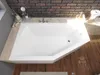 A white corner bathtub is shown from a top-down perspective, set against a brick wall and wooden floor. Voir les images du produit