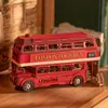 A wooden model of a red London double-decker bus is displayed on a wooden surface, with books and papers in the background. Anteprima dell’immagine prodotto