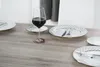 A wine glass with red wine spilled on a wooden table, set with plates and cutlery. Podgląd zdjęcia produktu
